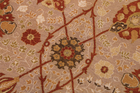A close-up of a patterned textile or rug showing a beige background with red, rust, olive green, and cream floral and geometric motifs.
