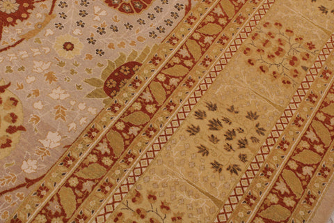 A close-up of an ornate patterned rug with beige, gold, and rust-red floral and geometric motifs.